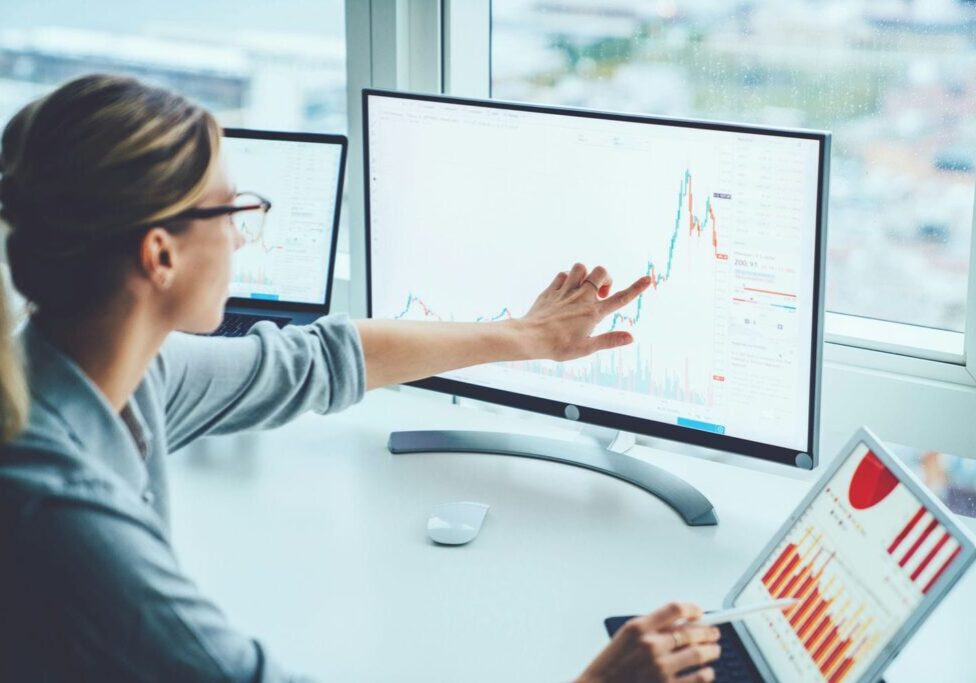 corporate woman pointing at graph trending upwards